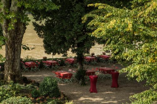 a group of red tables and chairs under trees at Hotel Leyscher Hof in Leutesdorf