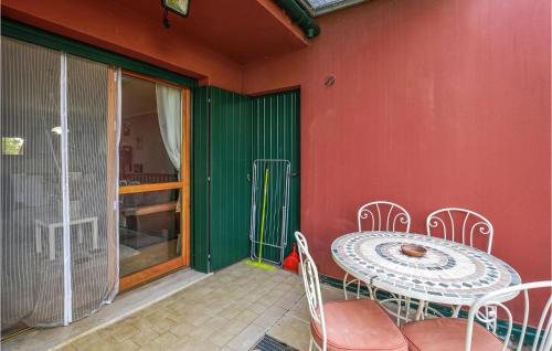 a patio with a table and chairs on a red wall at Nice Apartment In Aprilia Marittima in Aprilia Marittima