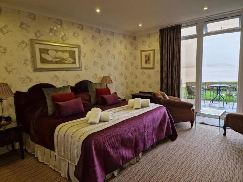 um quarto com uma cama grande e uma janela grande em Balcary Bay Country House Hotel em Auchencairn