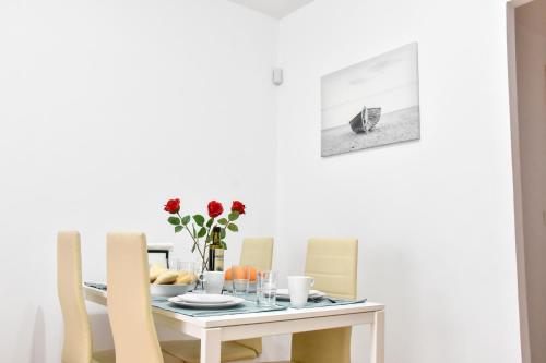 a white dining room table with chairs and a table with flowers at Amplio con Parking, Club y Piscina junto a Sevilla in La Algaba