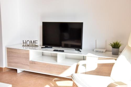 a living room with a tv on a white entertainment center at Amplio con Parking, Club y Piscina junto a Sevilla in La Algaba