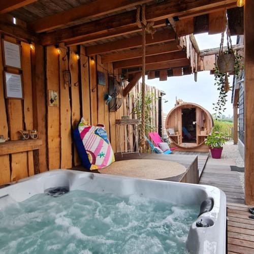 a bath tub in a wooden house with a patio at wellness chalet met jacuzzi, sauna, omheinde tuin, in Sint Annaland