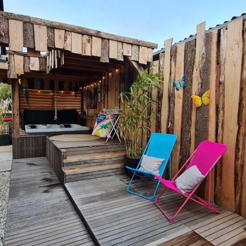 two chairs sitting on a wooden deck with a fence at wellness chalet met jacuzzi, sauna, omheinde tuin, in Sint Annaland