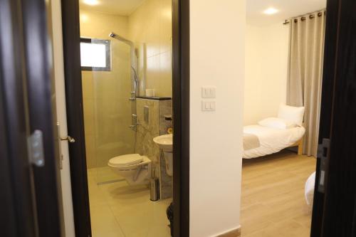 a bathroom with a toilet and a sink and a bed at Follow Sea Villa in Sowayma