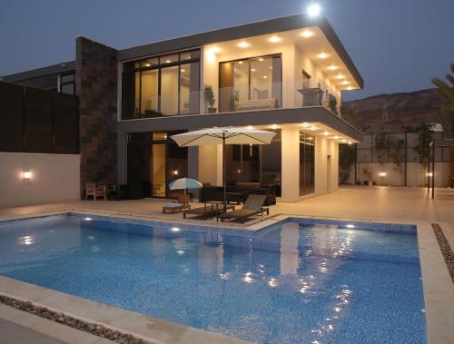 a house with a swimming pool in front of a house at Follow Sea Villa in Sowayma