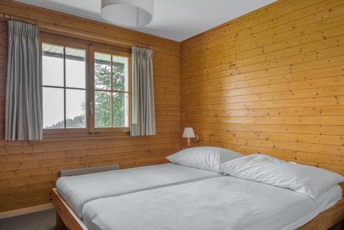 een slaapkamer met een bed met houten wanden en een raam bij Tschiffra EG in Bettmeralp