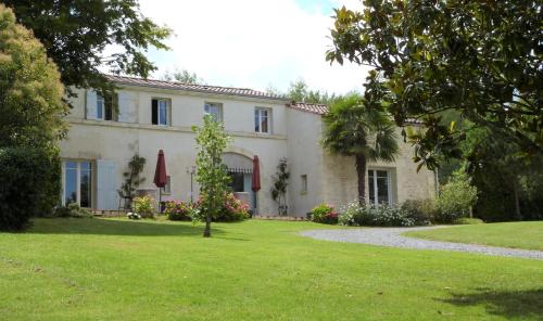 une maison avec une pelouse verte devant elle dans l'établissement Le Logis de La Brumanderie - Saintes, à Fontcouverte