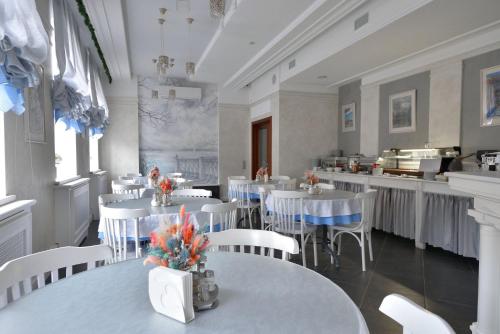 a dining room with white tables and white chairs at Rachmaninoff Hotel in Velikiy Novgorod