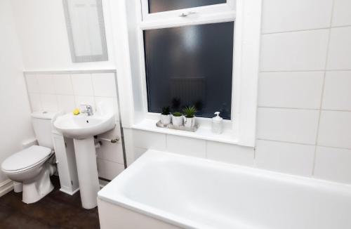 a white bathroom with a toilet and a sink at Cozyhouses in Hull