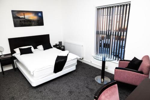 um quarto com uma cama branca e 2 cadeiras em Cozyhouses em Hull