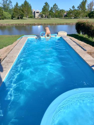 un hombre está en una piscina en un lago en Relax frente al Lago en Oliveros