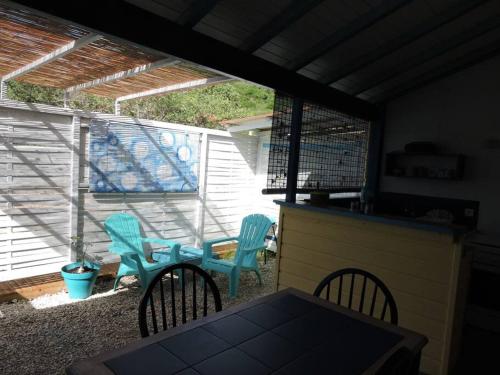a patio with chairs and a table and a bird cage at Gîtes tit'anse Léo et l'eau, piscine commune in Cadet