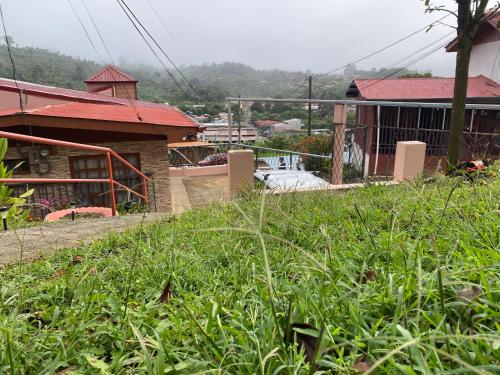 a field of grass with a house in the background at Casa entre la naturaleza in San Marcos