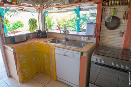 a small kitchen with a sink and a stove at La Maison Créole, les gîtes titanse, 3 chambres. in Cadet