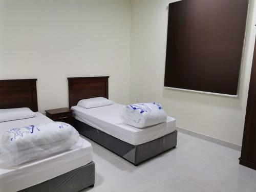 two twin beds in a room with a mirror at Al Basam Furnished Units in Yanbu