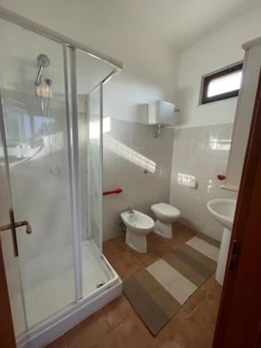 a bathroom with a glass shower and a toilet at Sa Covula in Alghero