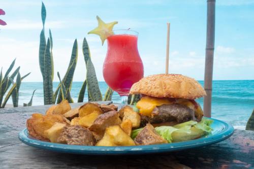 a plate of food with a burger and chips and a drink at Finca Escondida in Palomino