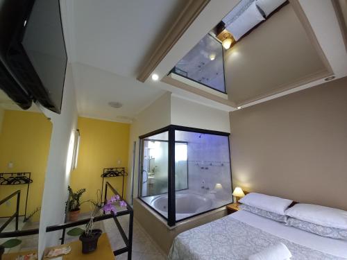 1 dormitorio con ventana grande y bañera en Miragem Chalés, en Serra Negra