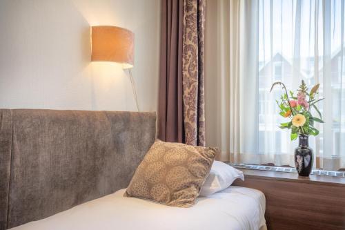 a bedroom with a couch and a window with a vase of flowers at Hotel Milano in Rotterdam
