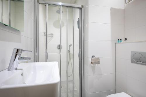 a white bathroom with a shower and a sink at Hotel Milano in Rotterdam