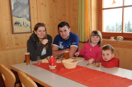 une famille assise à une table avec un enfant dans l'établissement Mecki's Dolomiten Panorama Stubn, à Debant