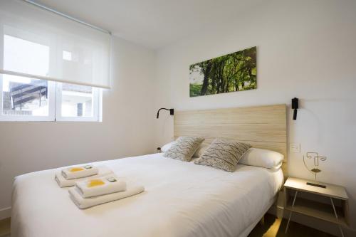 a bedroom with a white bed with two towels on it at OLABIDE 2 by Smiling Rentals in Hondarribia