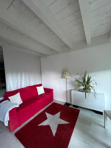 uma sala de estar com um sofá vermelho e um tapete estelar em Villa Natura appartamento Open Space con giardino em Trento