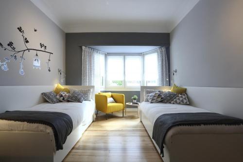 a bedroom with two beds and a yellow chair at Etxarri by Smiling Rentals in Hondarribia