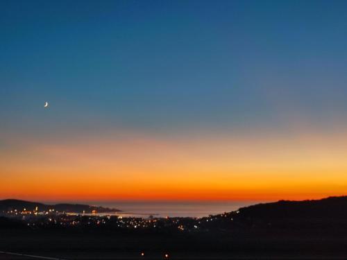 een zonsondergang boven de oceaan met de maan in de lucht bij Holiday home N&S in Bar