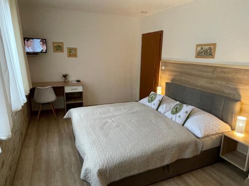 a bedroom with a bed and a desk and a television at Penzión Pod Guglom in Mlynky 