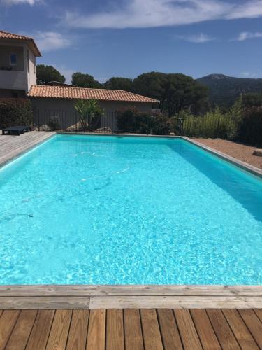 une grande piscine bleue avec une terrasse en bois dans l'établissement Appartement proche des plus belles plages, à Porto-Vecchio