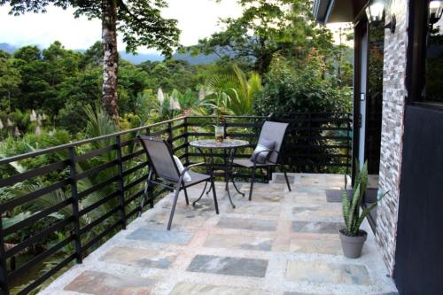 a patio with two chairs and a table on a balcony at Río Celeste Nature View in Upala