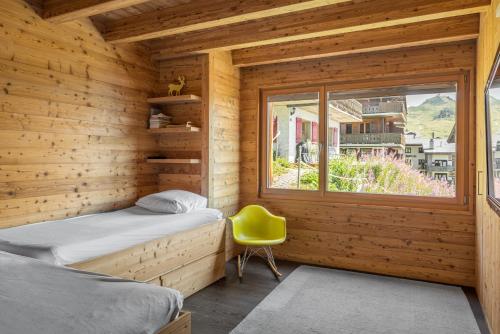 Cabaña de madera con 2 camas y silla amarilla en Nachtigall OG, en Bettmeralp