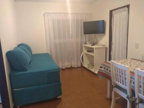 a living room with a blue chair and a television at Depto para 4 Pinamar centro NO Grupos jóvenes in Pinamar