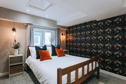 a bedroom with a large white bed with orange pillows at The Lighthouse, Boutique apartment in the town centre in Tavistock
