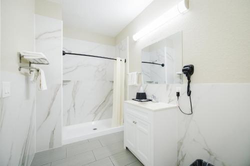 a white bathroom with a shower and a sink at Winchester Inn and Suites Humble/IAH/North Houston in Humble
