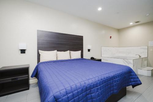 a hotel room with a blue bed and a sink at Winchester Inn and Suites Humble/IAH/North Houston in Humble