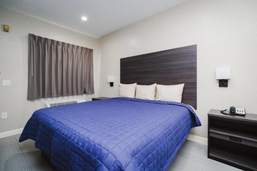 a hotel room with a blue bed and a window at Winchester Inn and Suites Humble/IAH/North Houston in Humble