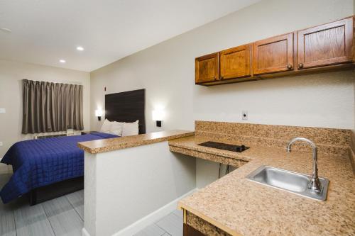 una cocina con fregadero y una cama en una habitación en Winchester Inn and Suites Humble/IAH/North Houston, en Humble