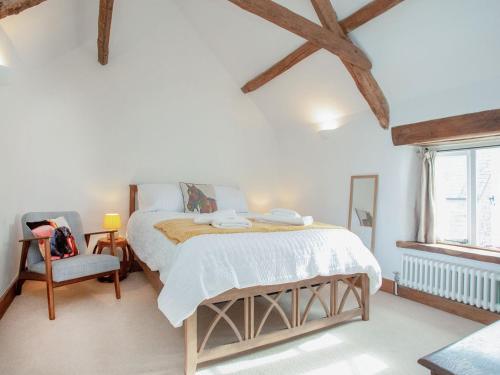 a bedroom with a bed and a chair and a window at Welcome Cottage in Woolfardisworthy