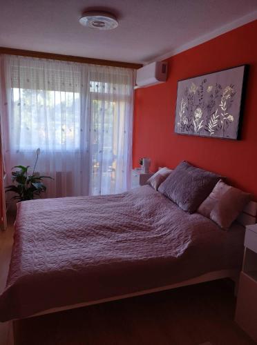 ein Schlafzimmer mit einem großen Bett mit einer roten Wand in der Unterkunft Pihenő Zug Apartman in Budapest