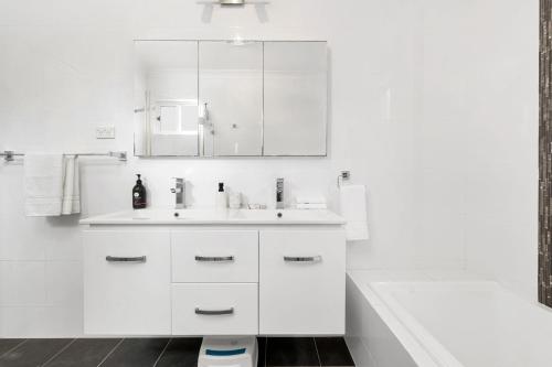 ein weißes Badezimmer mit Waschbecken und Spiegel in der Unterkunft Seahaven Gerringong in Gerringong