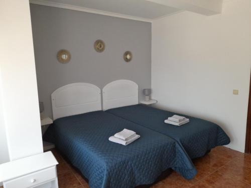 una camera da letto con un letto blu con due asciugamani sopra di Apartamentos Serranheira a Costa de Santo André