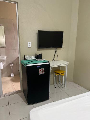 a bathroom with a television and a desk with a small refrigerator at Pousada da Celma in Fortaleza