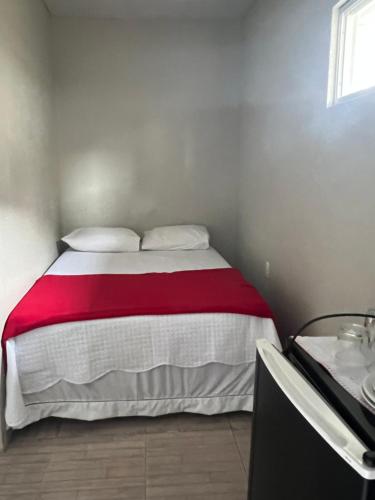 a bedroom with a bed with a red and white blanket at Pousada da Celma in Fortaleza