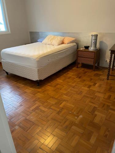 een slaapkamer met een bed en een houten vloer bij Vista Maravilhosa Pitangueiras in Guarujá