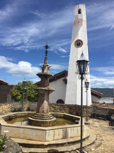 a fountain in front of a building with a clock tower at HOSPEDAJE DE GUATAVITA in Guatavita