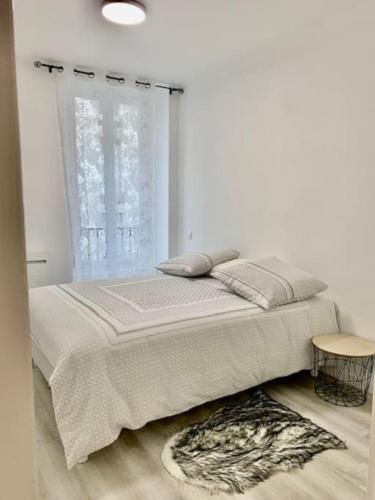 un lit dans une chambre blanche avec une fenêtre dans l'établissement Gold Europole-Gare, à Grenoble