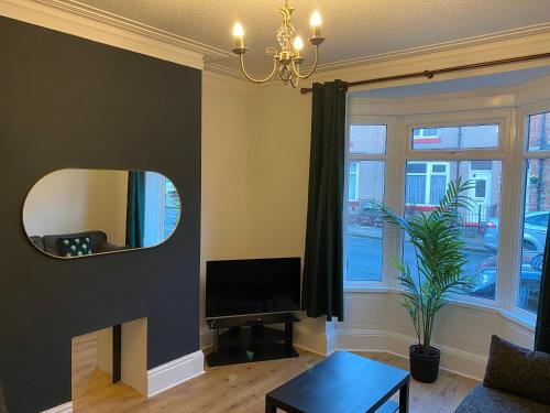 a living room with a mirror and a tv at Thornton - Stylish 3 bed terraced house with free parking in Darlington