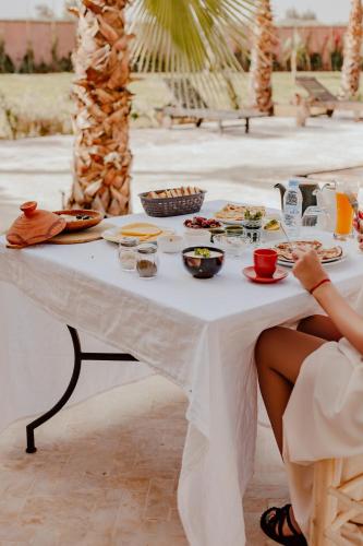 a woman sitting at a table with food on it at Aghmat Lodge Guest house in Marrakech